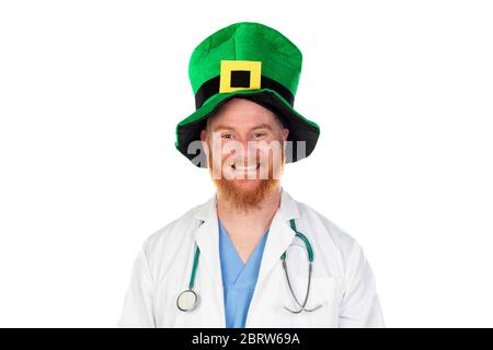 Medico di testa rossa con cappello verde guardando la macchina fotografica isolata su uno sfondo bianco Foto Stock