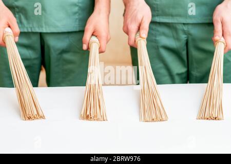 Primo piano di due massaggiatori che tengono le ginette di massaggio di bambù sul tavolo. Foto Stock