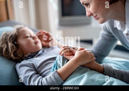 Madre che si prende cura di visitare la figlia di bambina in letto in ospedale. Foto Stock