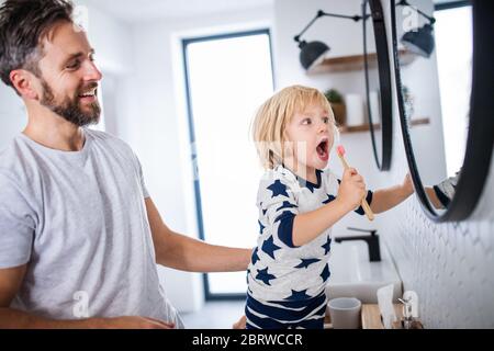 Padre maturo con figlio piccolo in bagno, denti spazzolanti. Foto Stock