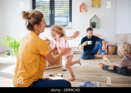 Famiglia giovane con due bambini piccoli all'interno in camera da letto giocando. Foto Stock