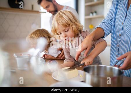 Giovane famiglia con due bambini piccoli in cucina, preparando il cibo. Foto Stock