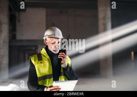 Uomo ingegnere che usa walkie talkie sul cantiere. Foto Stock