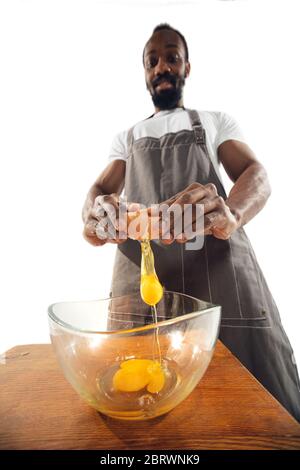 Incredibile afroamericano uomo preparare cibo incredibile con azione, dettagli ed emozioni luminose, cuoco professionista isolato su sfondo bianco studio. Cucina moderna, opere d'arte. Primo piano, grandangolo. Foto Stock