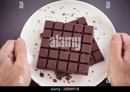 Uomo che tiene un piatto bianco con cioccolato fondente fatto in casa sulle sue mani. Primo piano. Foto Stock