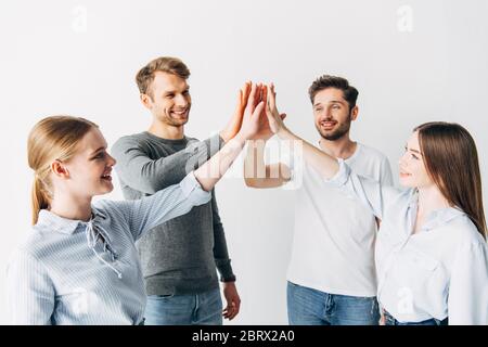 Giovani collaboratori alti cinque e sorridenti in ufficio Foto Stock