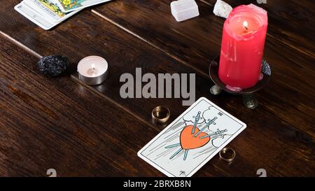 New York, USA-19.05.2020: Gli anelli di nozze con le schede di fortuna-che dicono, le candele illuminate e le pietre magiche sono sul tavolo. Fortune che dice per amore su rel Foto Stock