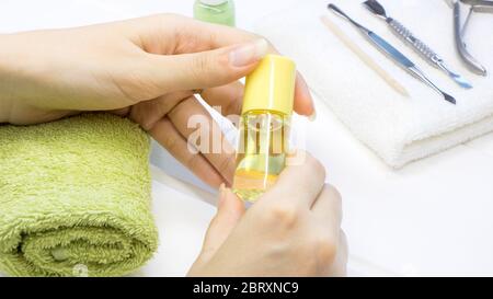 Manicure. Una donna tiene l'olio della cuticola. Attrezzi per manicure. Idratante alla cuticola. Cura delle unghie, SPA, bellezza. Unghie naturali lunghe. Salone di bellezza. Foto Stock