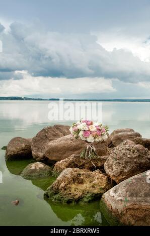 bouquet di rose bianche e viola su pietre Foto Stock