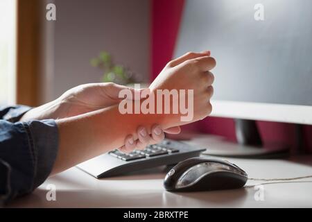 La sindrome di Office - Giovani donne che soffrono di dolori a mano mentre si utilizza il computer al lavoro. Professionali di fattore di rischio. Medico e sanitario concetto. Foto Stock