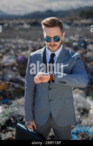 Uomo d'affari moderno in discarica, consumismo contro concetto di inquinamento. Foto Stock