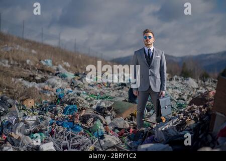 Uomo d'affari moderno in discarica, consumismo contro concetto di inquinamento. Foto Stock