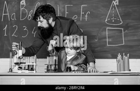 Insegnante uomo con little boy. La scuola le attrezzature di laboratorio. studente facendo esperimenti scientifici con microscopio in laboratorio. Si torna a scuola. il padre e il figlio a scuola. usando microscopio in laboratorio. Vivere in epoca digitale. Foto Stock