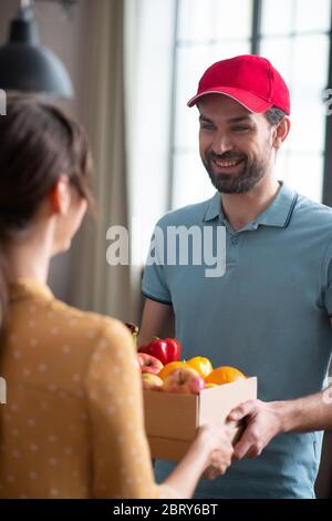 Cliente femminile dai capelli scuri che riceve generi alimentari dal corriere Foto Stock