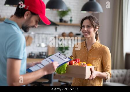 Giovane Courier maschio in un cappello rosso guardando la lettera di vettura Foto Stock