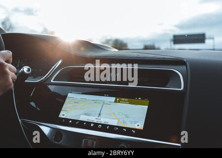 Vista in primo piano del sistema di navigazione con luce soffusa al tramonto sopra la console centrale dell'auto. Essere sulla strada con il percorso visualizzato sul sistema di navigazione Foto Stock