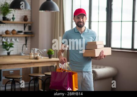 Persona di consegna in un cappello rosso che tiene le scatole Foto Stock