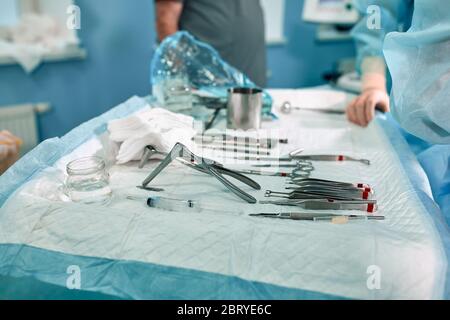 Strumenti sterili sul tavolo operatorio, luce blu, vera sala operatoria. Foto Stock
