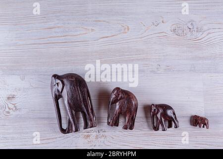 Elefanti fatti a mano in legno su sfondo bianco di legno Foto Stock