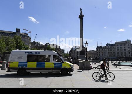 Un ciclista passa un pulmino di polizia a Trafalgar Square, Londra, dopo l'introduzione di misure per portare il paese fuori dalla chiusura. Foto Stock