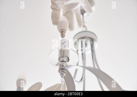 Donna installa le luci a LED nel nuovo lampadario a soffitto Foto Stock