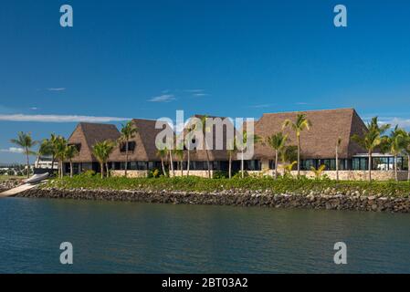 Tipici bungalow fijiani con palme sotto un cielo blu, di fronte al mare. Figi Foto Stock