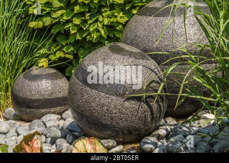 Splendido giardino. Fontana d'acqua con tre pietre rotonde. Foto Stock