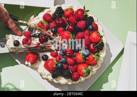 Vista dall'alto sulla splendida torta estiva decorata con frutti di bosco tagliati e serviti. Foto Stock