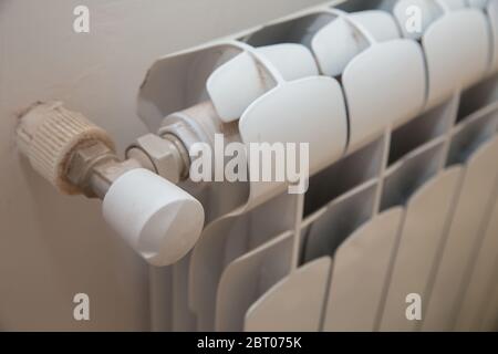 Primo piano di kop del riscaldatore in casa, attrezzatura idraulica . Riscaldatore. Radiatore bianco con termostato sotto il finestrino di casa . Riscaldamento del radiatore a casa Foto Stock