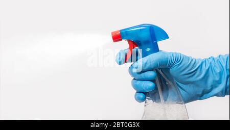 Indossare un guanto protettivo blu che contiene una bottiglia spray con disinfettante. Concetto di disinfezione o igiene sull'epidemia di Coronavirus. Sfondo bianco. COP Foto Stock