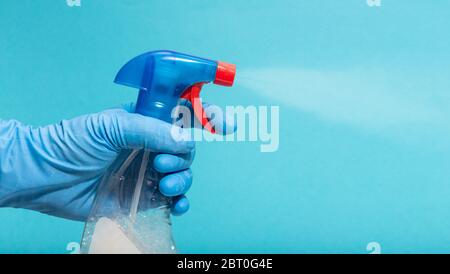 Disinfettante spray protettivo per guanti. Concetto di disinfezione o igiene sull'epidemia di Coronavirus. Sfondo blu. Spazio di copia Foto Stock