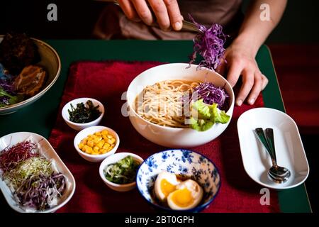 Primo piano di uno chef che prepara la zuppa Ramen Noodle in un ristorante Ramen e Gyoza in Italia. Foto Stock