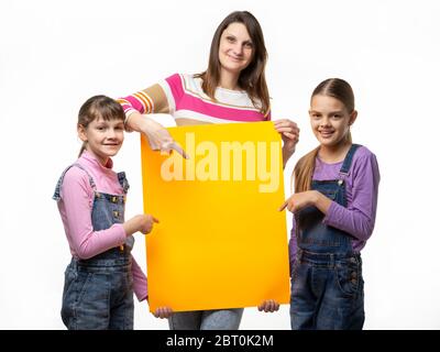 Mamma e due figlie tengono un segno arancione nelle loro mani e puntano ad esso Foto Stock