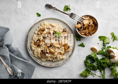 Un piatto di cucina italiana - risotto di riso e funghi. Vista dall'alto. Disposizione piatta. Sfondo chiaro. Foto Stock