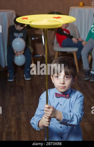 Bambino che gira bianco, blu, piatti . Divertimento con i piatti di filatura. Equilibrando un piatto di filatura. I bambini imparano a giocare a tavola rotante . Baku, Azerbaigian Foto Stock