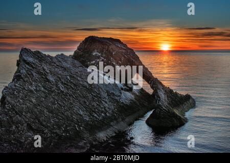 ARCO FIDDLE ROCK PORTKNOCKIE MORAY COSTA SCOZIA MATTINA PRESTO ALBA UN SOLE CHE SORGE SULL'ARCO Foto Stock