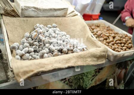 Gustose castagne arrostite fotografate accanto alle castagne crude vendute in Portogallo Foto Stock