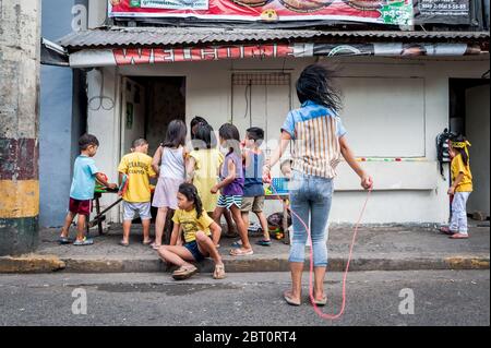 I bambini filippini giocano per strada nella vecchia città murata di Intramuros, Manila, Filippine. Foto Stock