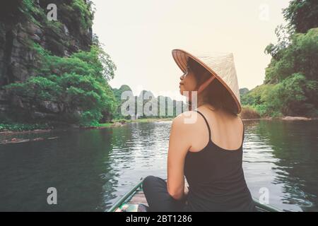 Donna asiatica seduta su una barca di legno durante la sua vacanza nella provincia di Ninh Binh, Vietnam Foto Stock