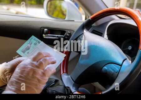 Scrivere una carta tagliando depositare il controllo di stimolo del governo con i guanti sopra per la sicurezza in automobile Foto Stock