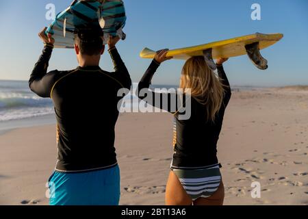 Coppia caucasica che tiene tavole da surf sulla spiaggia. Foto Stock