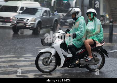 bangkok thailandia 10.10.2019 pioggia pesante in coppia bagnarsi su uno scooter Foto Stock