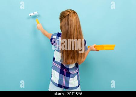 giovane adolescente dipinge una parete blu chiaro con un rullo di vernice. Foto Stock
