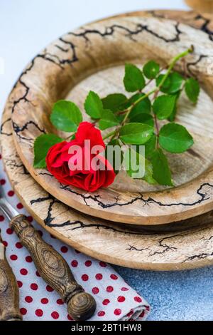 Tavolo con fiori di rosa rosso fresco su piatti di legno vintage su sfondo di pietra con spazio per la copia Foto Stock