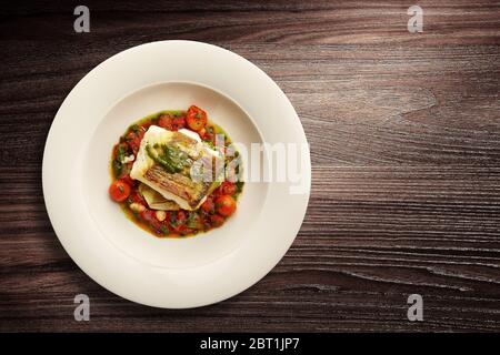 Direttamente sopra un'elegante piatto di pesce alla Nouvelle Cuisine su verdure su sfondo di legno Foto Stock