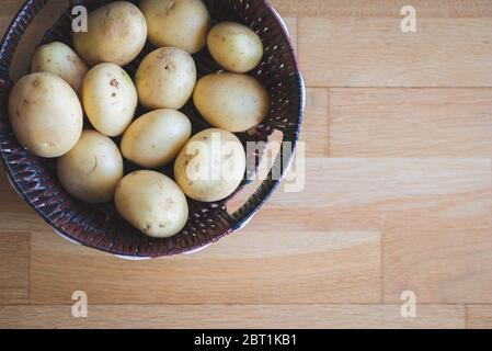 Patate in un cesto di vimini. Tuberi di patate in piatti di vimini e sparsi sul tavolo. Raccolta di patate. Verdure per una dieta sana. Foto Stock