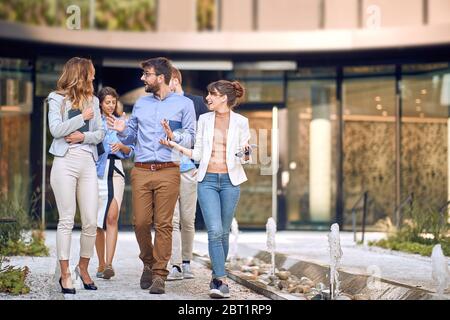 gruppo di giovani uomini d'affari che camminano di fronte all'edificio, lasciando l'incontro. Foto Stock