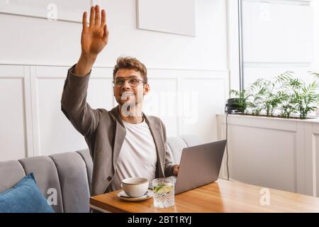 Bel giovane che salutava l'amico in un bar Foto Stock
