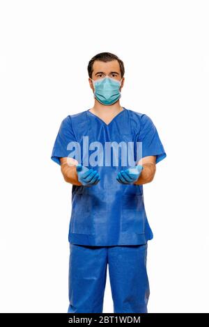 Medico maschile in scrub con maschera protettiva e guanti, che si allunga con mani aperte su fondo bianco chiaro. Concetto di coronavirus o covid 19 Foto Stock