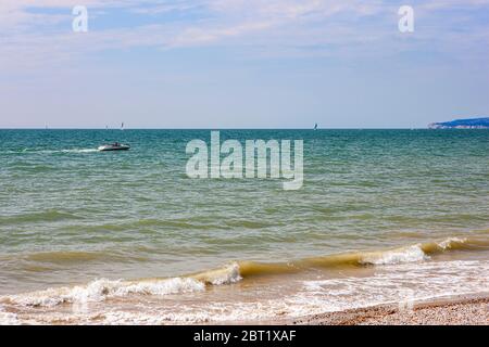 Barca a motore che naviga sul mare al largo della spiaggia di Camber Sands, vicino a Rye, Sussex Est in una calda mattina soleggiata in estate Foto Stock